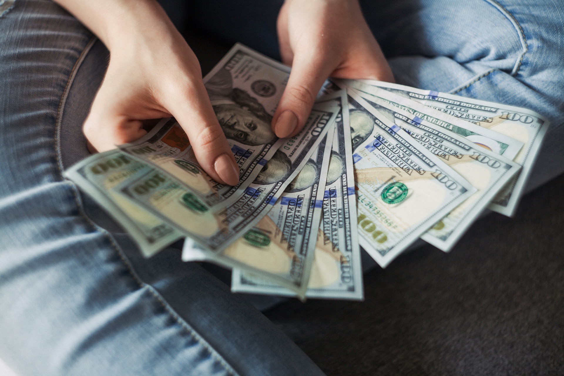 Hands counting hundred-dollar bills during a divorce asset dissipation review.