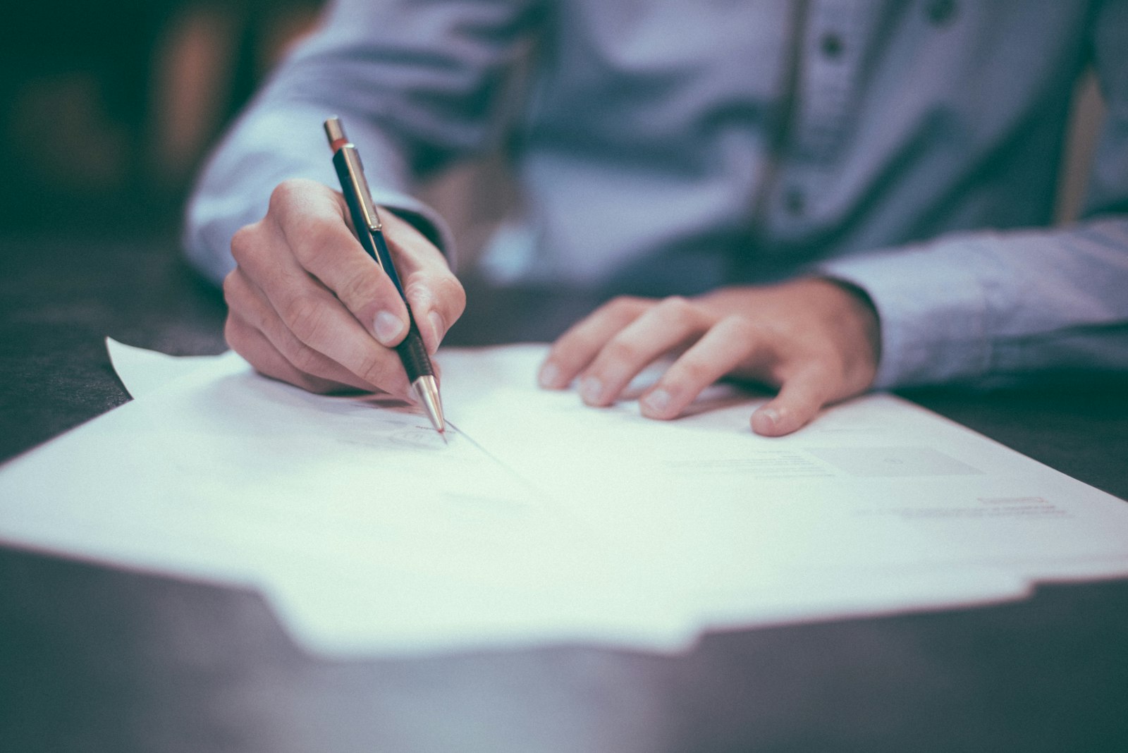 Hands signing a contract at a desk.